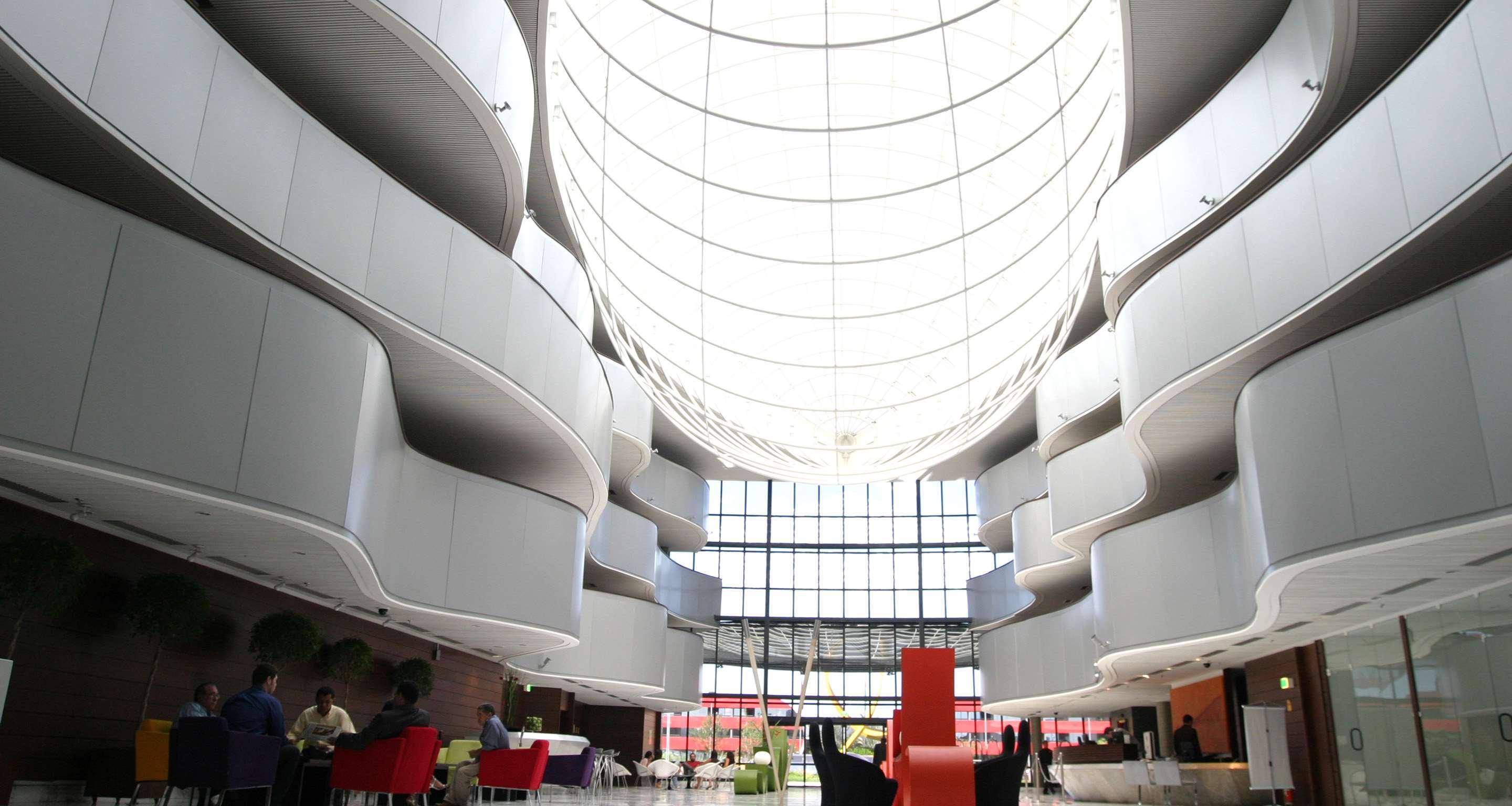 Royal Tulip Brasilia Alvorada Hotel Luaran gambar The photo depicts a modern interior space characterized by sleek, curvilinear architecture. The ceiling features a large, dome-like skylight that allows natural light to flood the area. The walls display a minimalist design with smooth, white surface