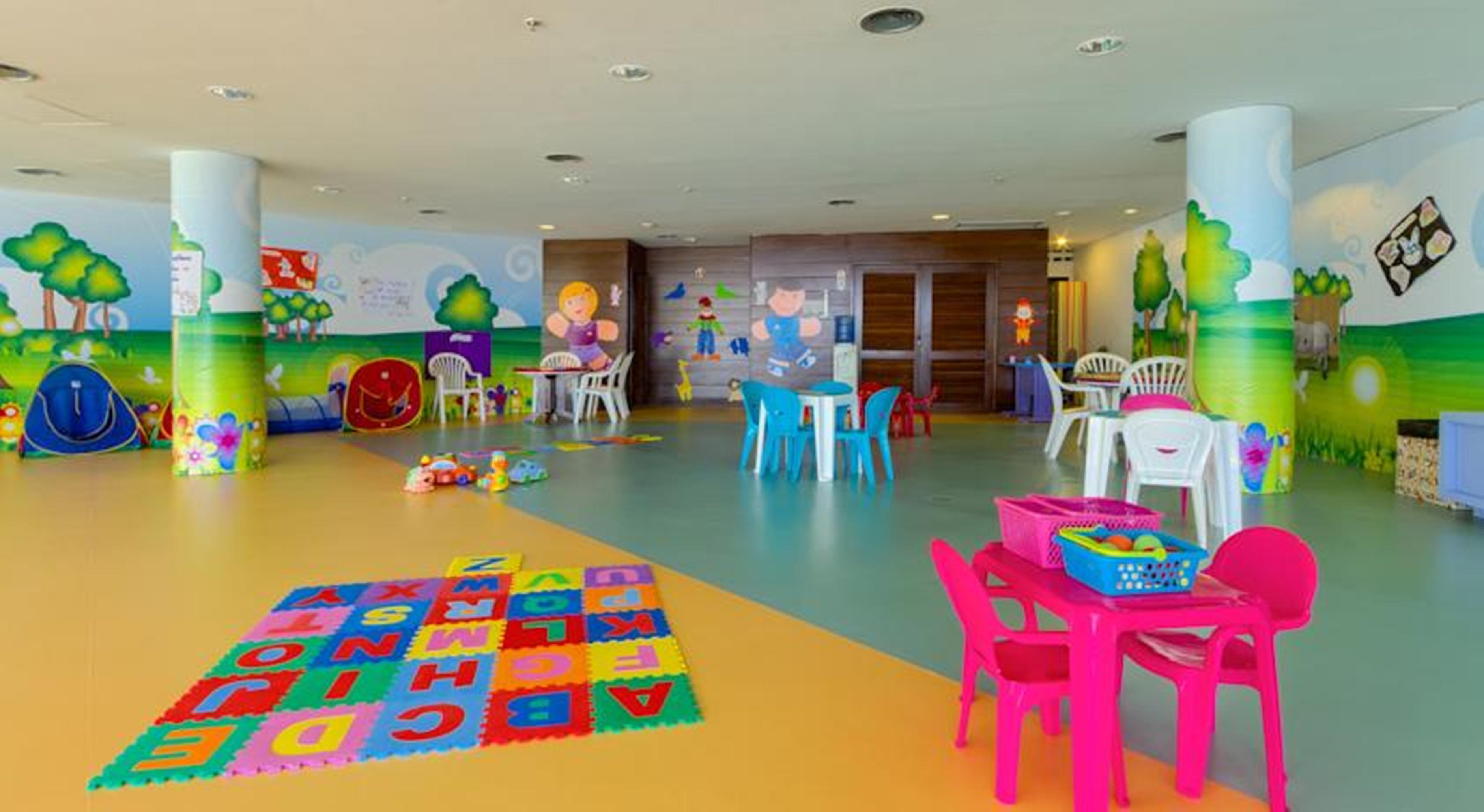 Royal Tulip Brasilia Alvorada Hotel Luaran gambar The photo shows a colorful and spacious children's playroom. The floor is divided into sections with different colors, and there is a large play mat featuring letters and numbers. 

In the room, there are several small, lightweight tables and chairs 